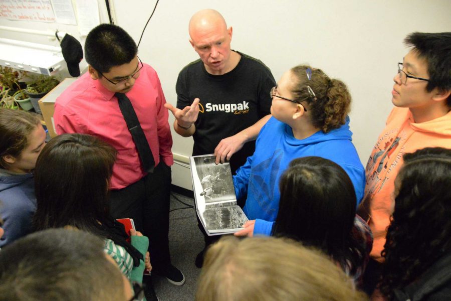 Ed Gold shows his book about Wales, Alaska, with the students in the journalism class.